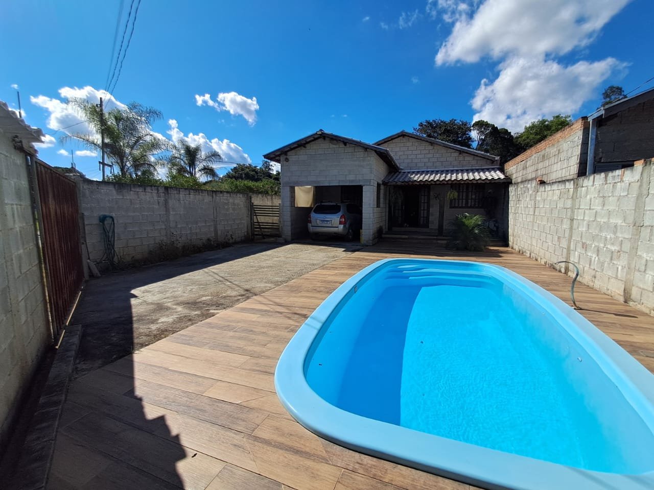 Piscina com deck e casa ao fundo, no sítio à venda em Pouso Alegre